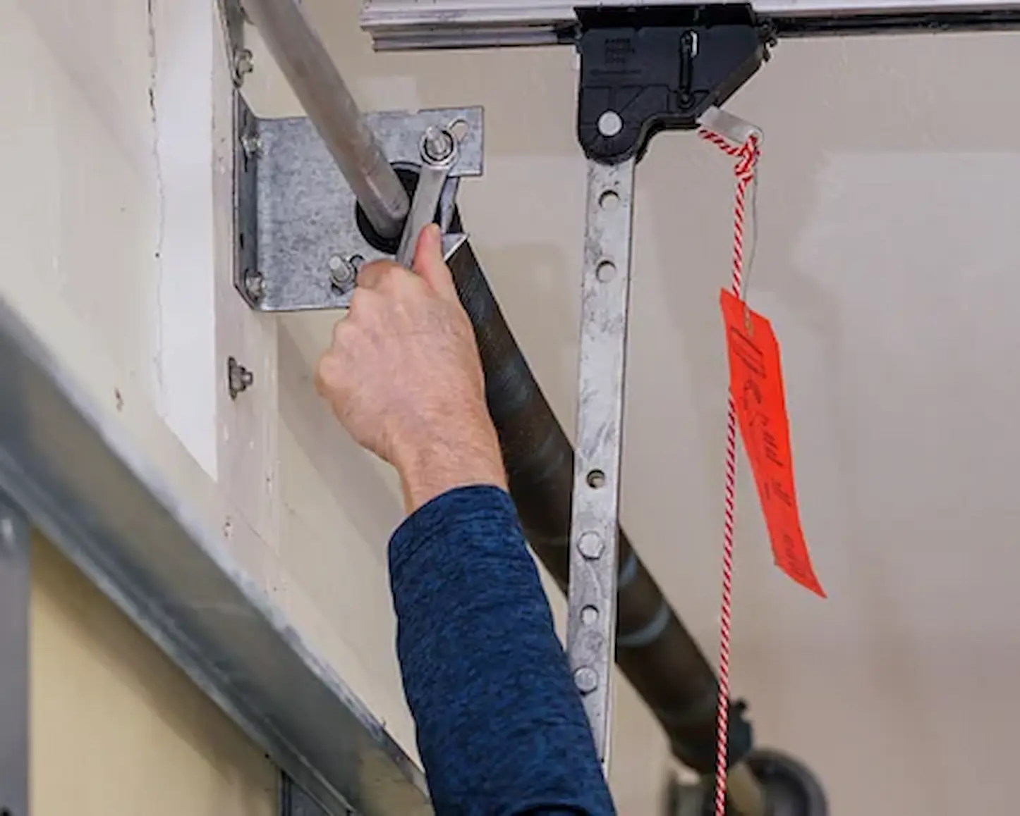 Garage door technician inspecting worn torsion springs to identify the cause of spring failure in Garland TX